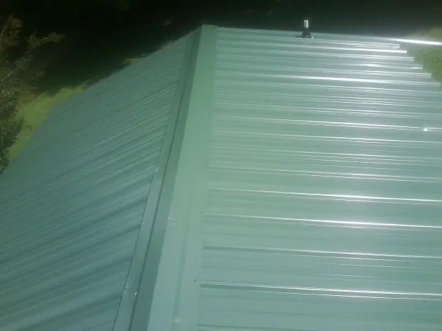 New green metal panels meeting at the ridge of a roof — Flat Roof Repair work by our crew in Oceanside