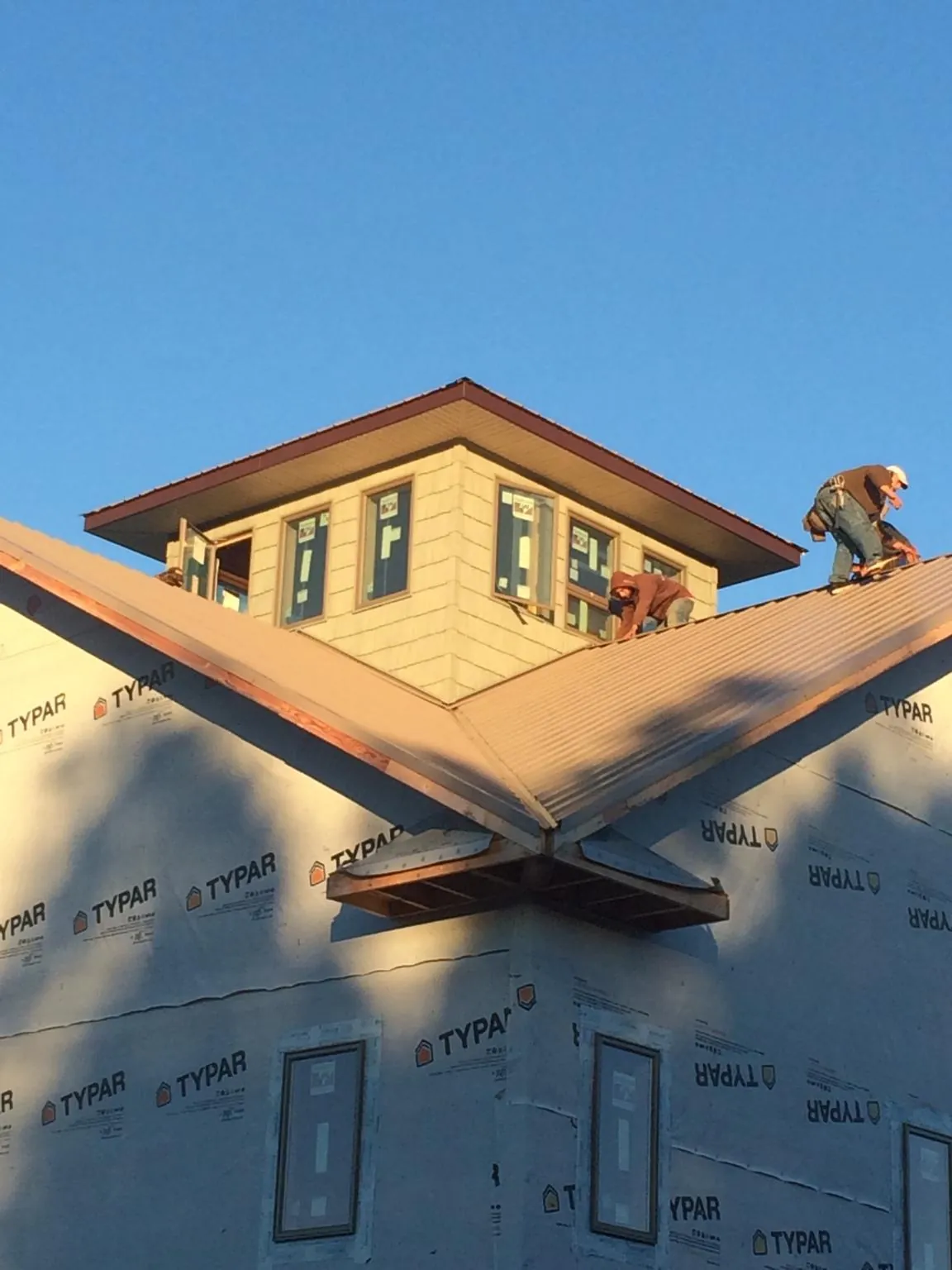 Roofers working around a rooftop cupola on a new metal roof at sunset — Roof Waterproofing in Oceanside by Roofing Brothers
